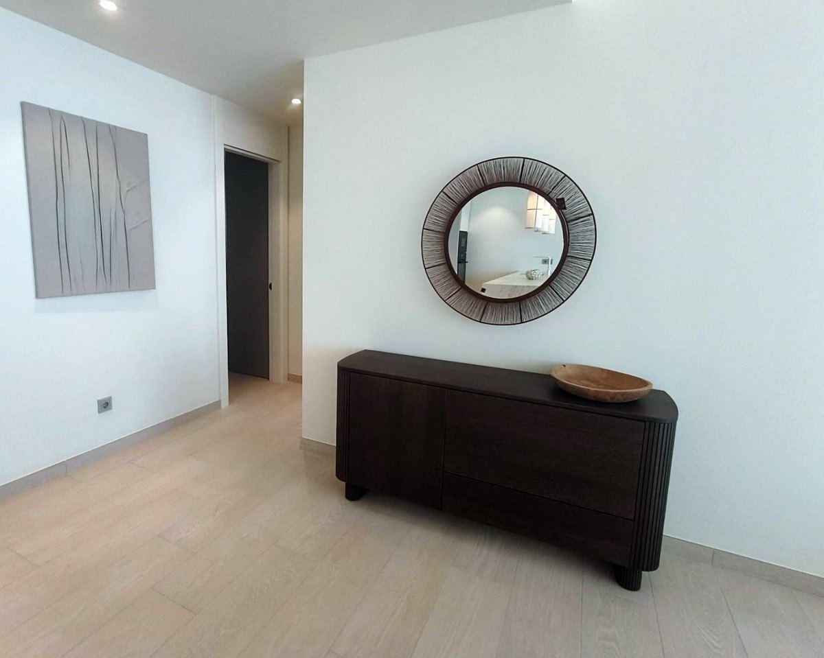 The hall with a round mirror over a dark sideboard