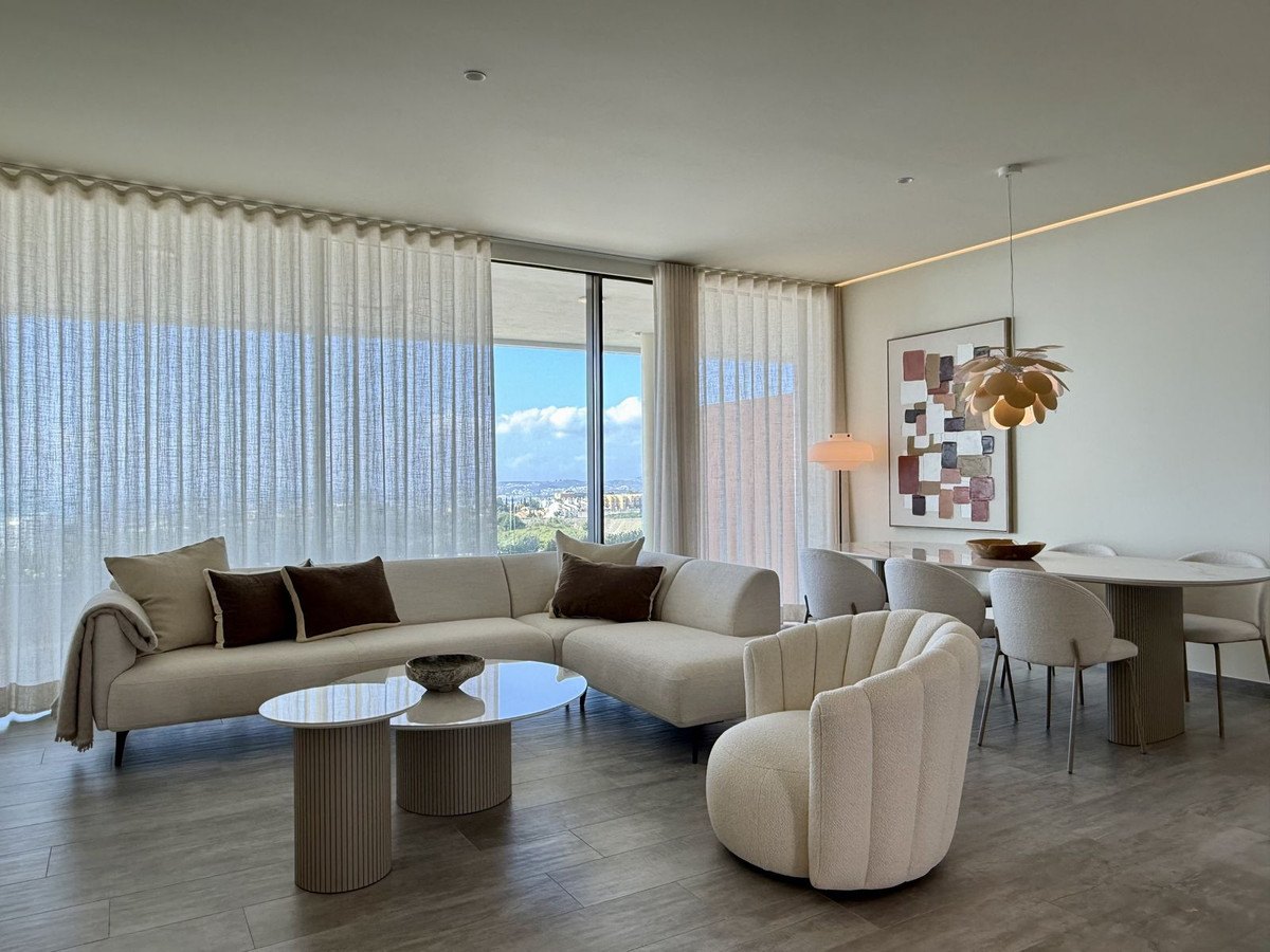 The living room behind full-height glass and sheer curtains